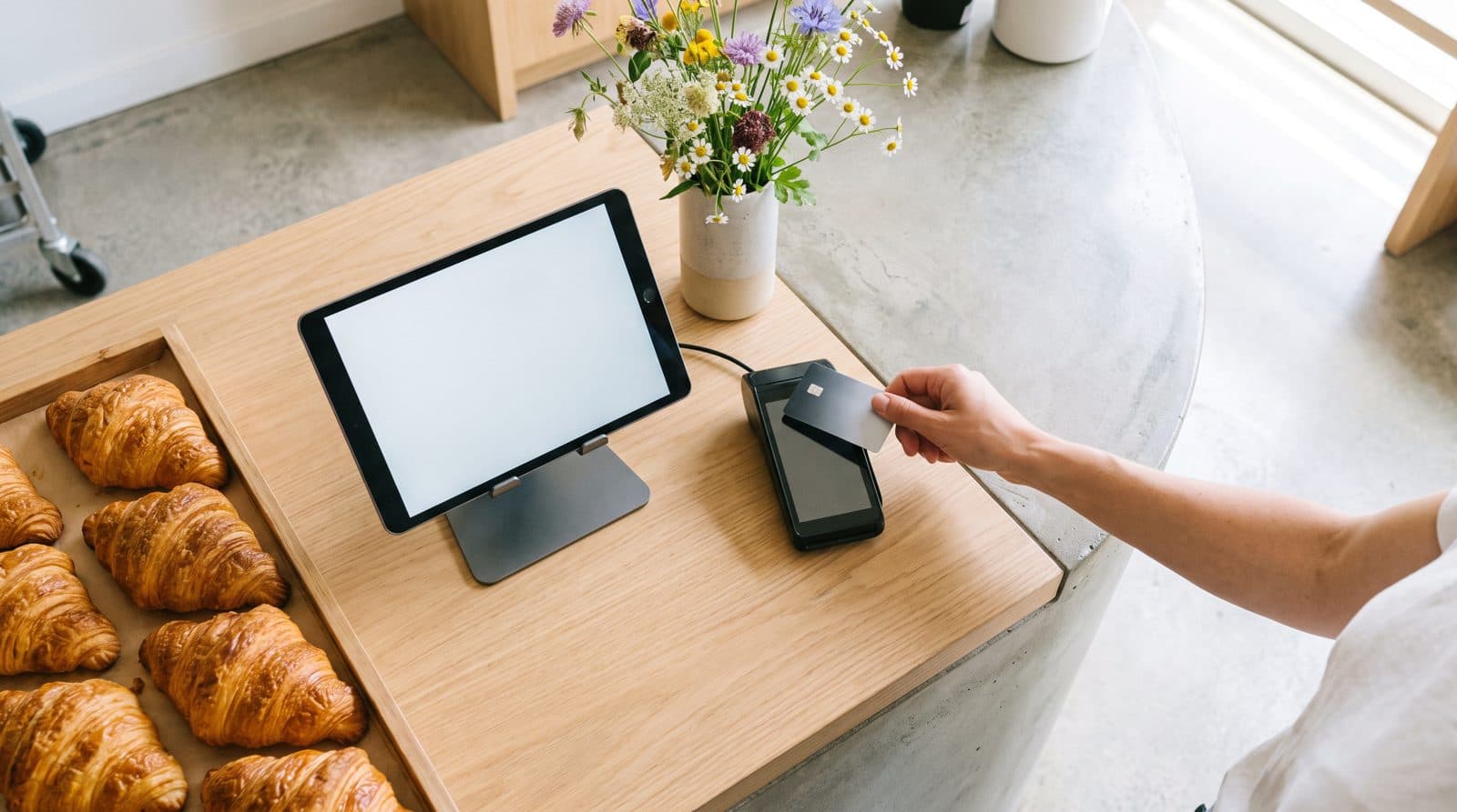 A bakery counter with a point of sale tablet and a terminal